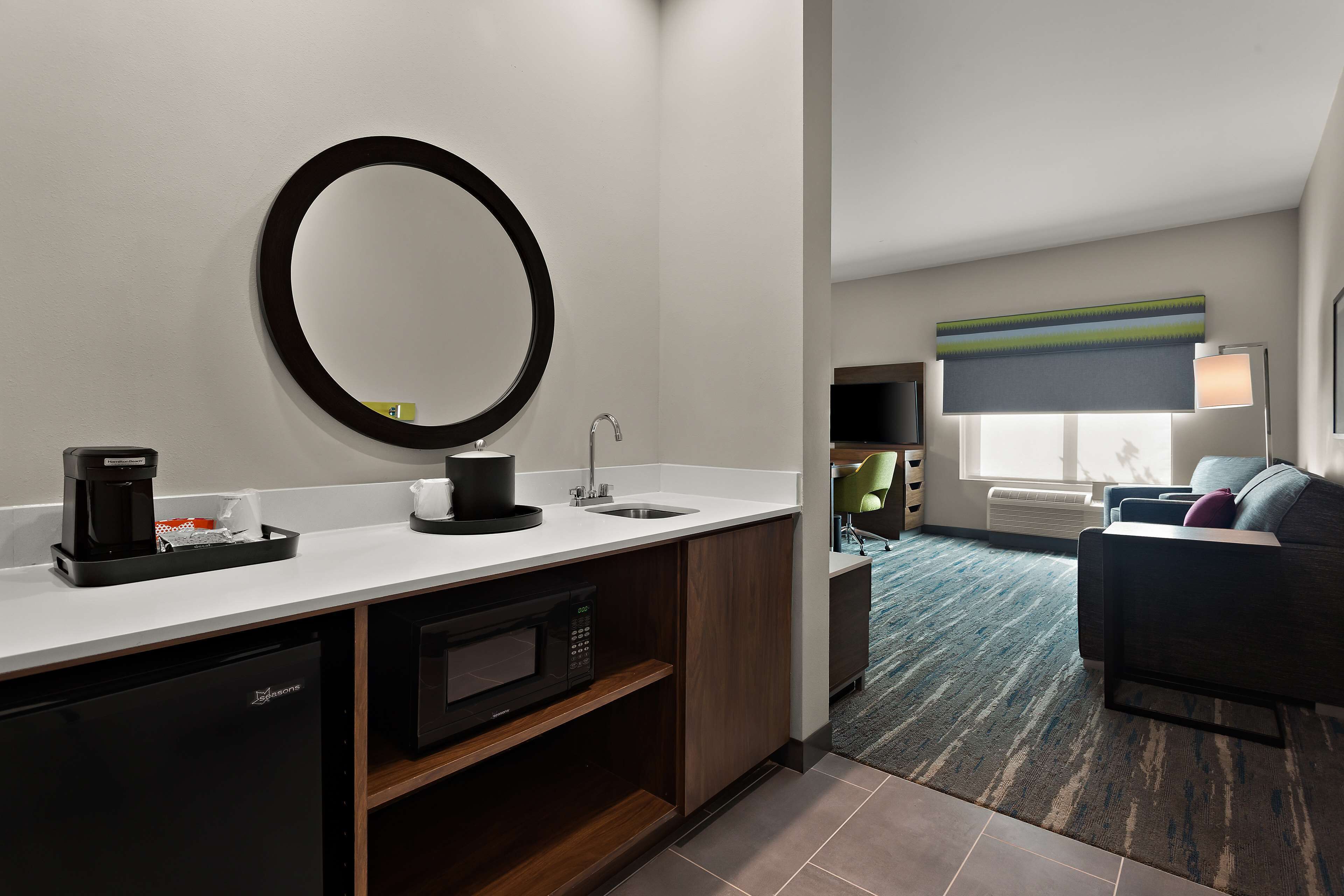 A modern hotel bathroom with a sink, mirror, and coffee maker.
