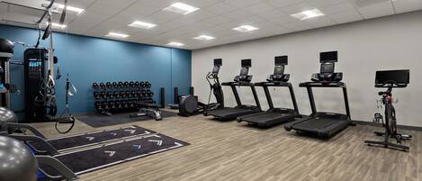 A gym with treadmills, elliptical machines, and free weights.