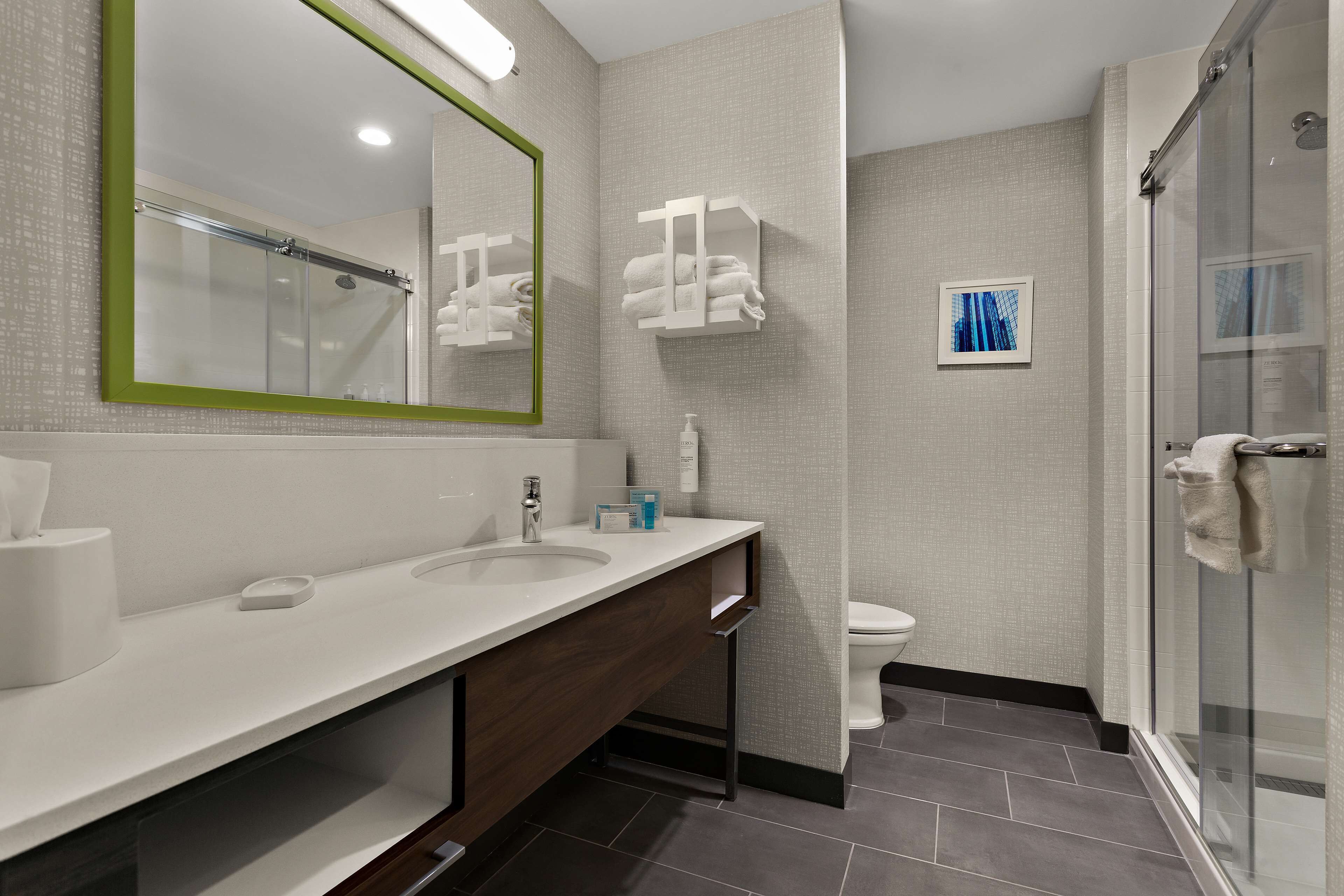 A modern bathroom with a large mirror, a sink, a toilet, and a shower area.