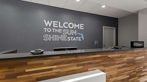 A reception desk with a wooden panel design and a welcome sign for Sun State. - Hampton Inn & Suites Ruskin I-75 (Ruskin)