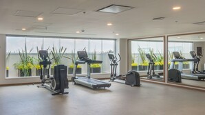 A gym with treadmills, stationary bikes, and weight machines, large windows with a view of greenery, and a clean, modern design. - Hampton by Hilton Aguascalientes Downtown (Aguascalientes)