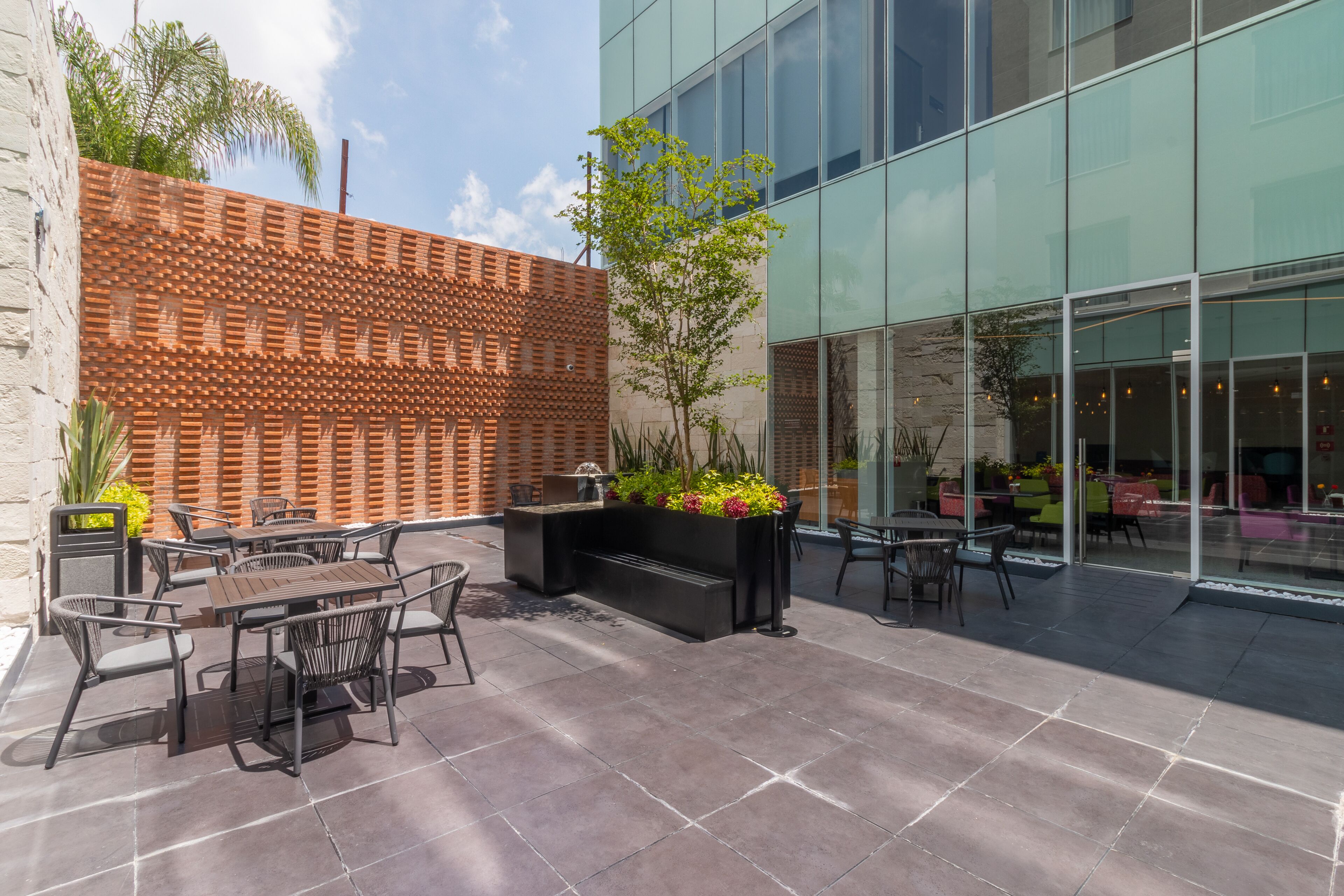 An outdoor patio area with a brick wall, seating, and a planter with flowers.
