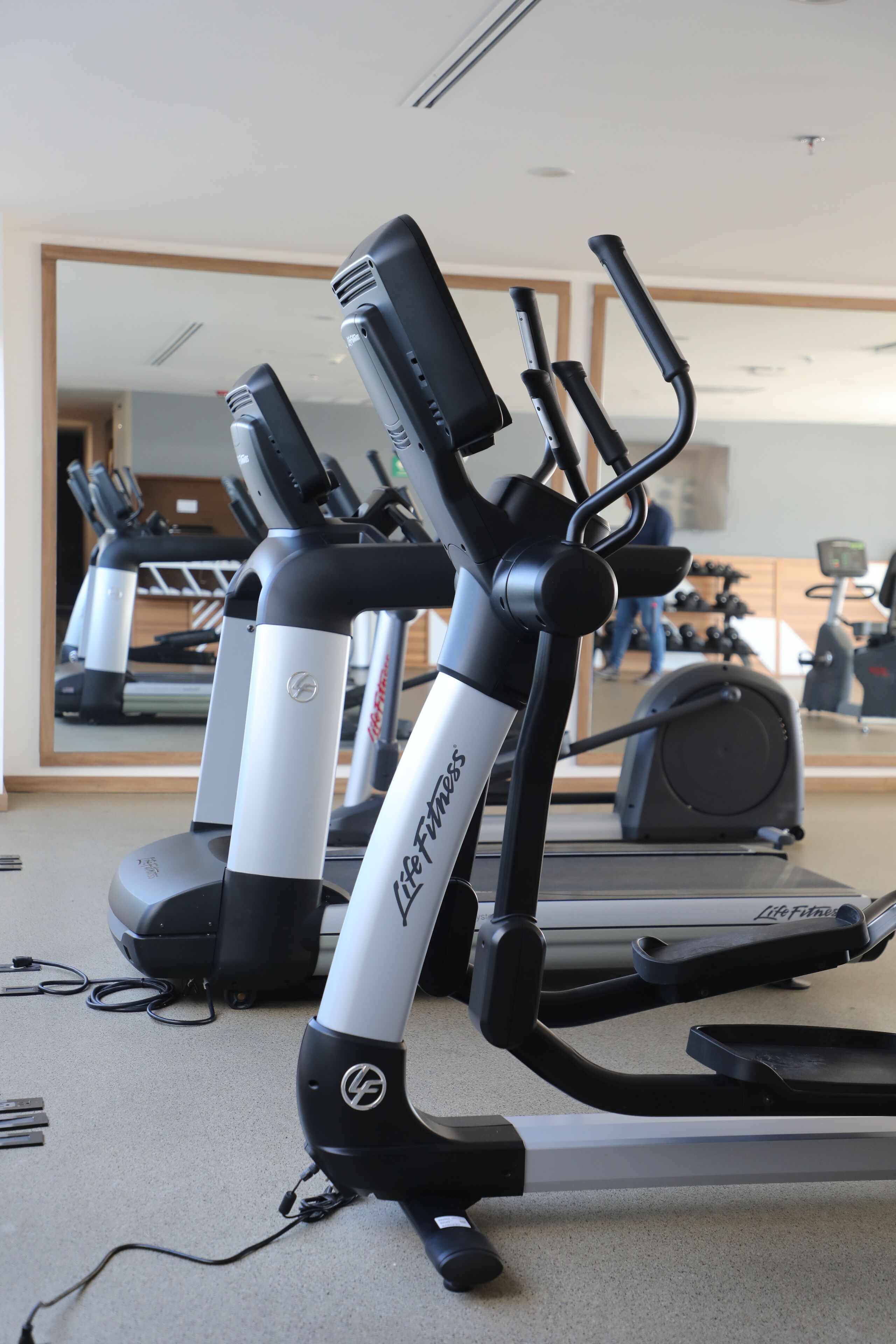 Un gimnasio con bicicletas estáticas y cintas de correr, incluyendo una máquina de la marca Life Fitness.