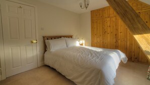 A bedroom with a bed, a wooden wardrobe, and a slanted ceiling. - 2 bedroom accommodation in Pickering (Pickering)