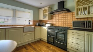 A kitchen with wooden flooring, white cabinets, a stove, a microwave, and a window with blinds. - 2 bedroom accommodation in Pickering (Pickering)