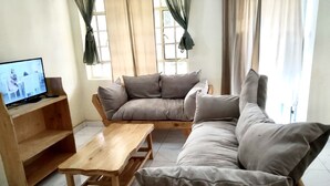 Una sala de estar con una mesa de centro de madera, un sofá y un televisor sobre un mueble de madera.