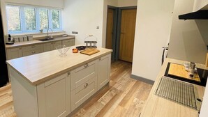 Une cuisine moderne dotée d’un grand îlot central, de planchers en bois et offrant une vue sur l’extérieur.
