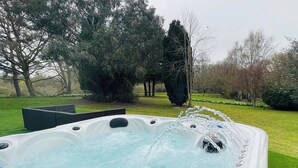 Un bain à remous avec de l’eau en circulation, entouré d’une pelouse et d’arbres.