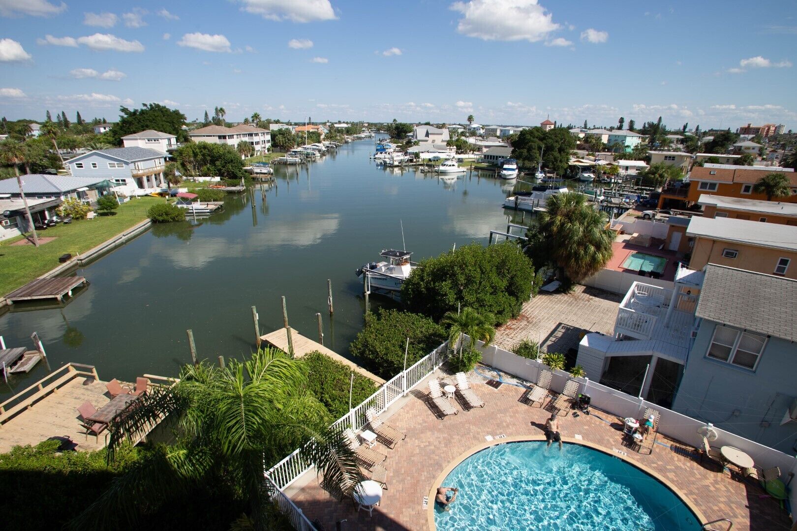 A residential area with a swimming pool, docked boats, and a river.