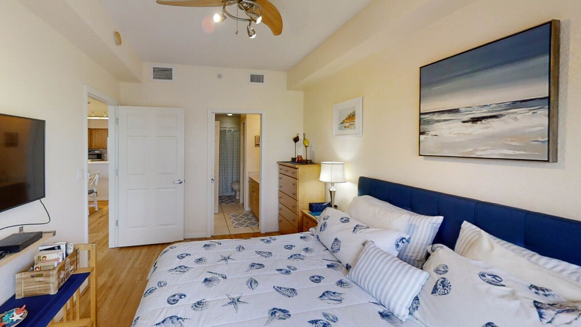Un dormitorio con cama, televisor, un cuadro y vistas al mar.