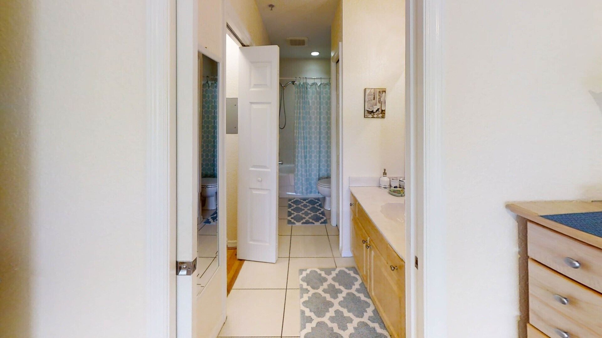 Un pasillo estrecho que conduce a un baño con ducha, inodoro y lavabo.