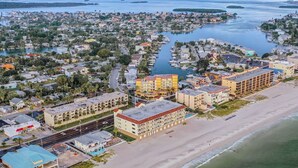 Luchtbeeld van een kustplaats met een jachthaven, hotels aan het strand en woonwijken.