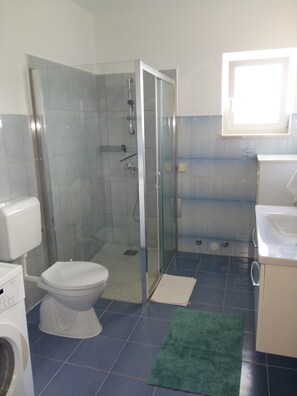 A bathroom with a glass-enclosed shower, a toilet, a washing machine, and a sink. - Big apt W.large Terrace&great sea View,close Beach (Trogir)