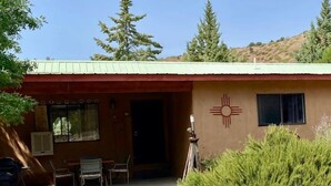 A building with a red roof, a door, and a window. There is a tree and a bush in front of the building. - #1 Casita Wild Mustang at the Catwalk, 2 BdRm Casita (Catron County)