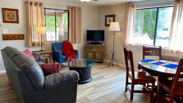A living room with a sofa, a TV, a dining table with chairs, a ceiling fan, and a window with curtains. - #1 Casita Wild Mustang at the Catwalk, 2 BdRm Casita (Catron County)