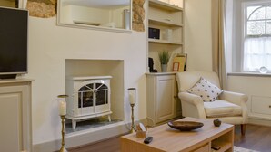 Una sala de estar con chimenea, televisor, sofá y mesa de centro.