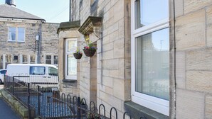 A stone building with hanging flower baskets, a white van parked in front, and a metal fence. - 3 bedroom accommodation in Amble, Morpeth (Amble, Morpeth)