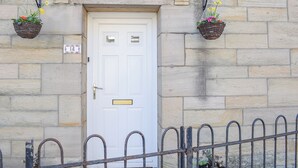 A white door with a small window above it, flanked by stone walls and a metal fence. - 3 bedroom accommodation in Amble, Morpeth (Amble, Morpeth)