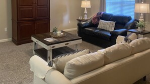 A living room with a ceiling fan, a dark brown cabinet, a white sofa, a blue leather couch, and a coffee table. - Close to Vaught Hemingway and Swayze (Oxford)