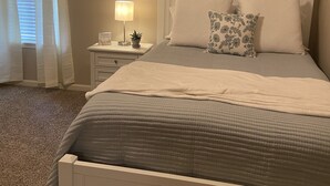 A bedroom with a bed, a nightstand, a lamp, and two framed botanical prints on the wall. - Close to Vaught Hemingway and Swayze (Oxford)