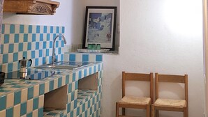 Eine Küche mit kariertem Fliesenrückwand, Holzbalken, einer Hängeleuchte und zwei Holzstühlen.