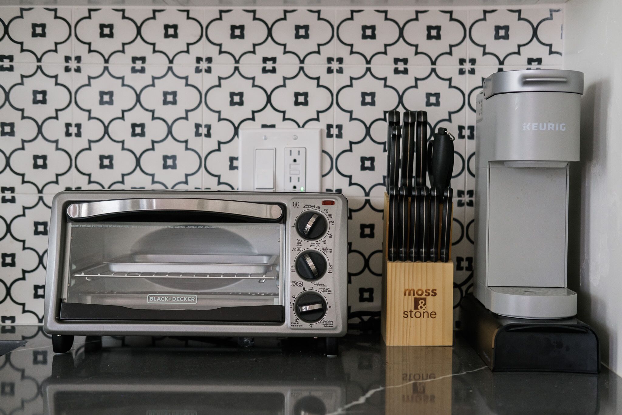 A kitchen with a toaster oven, a coffee maker, and a knife block.
