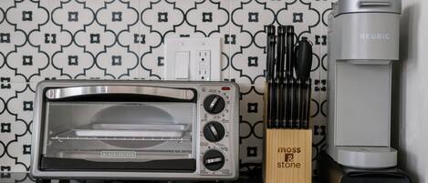A kitchen with a toaster oven, a coffee maker, and a knife block.