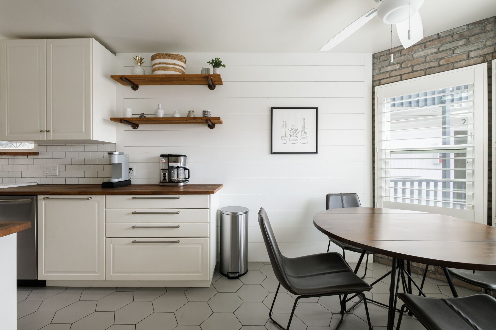 A kitchen with white cabinets, wooden countertops, and a dining area with a round table and chairs.