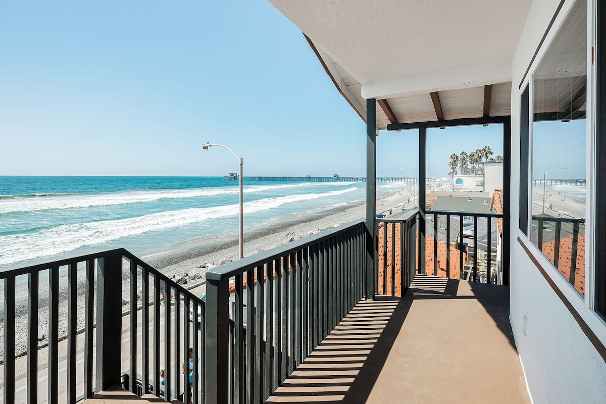 A balcony with a view of the beach and ocean.