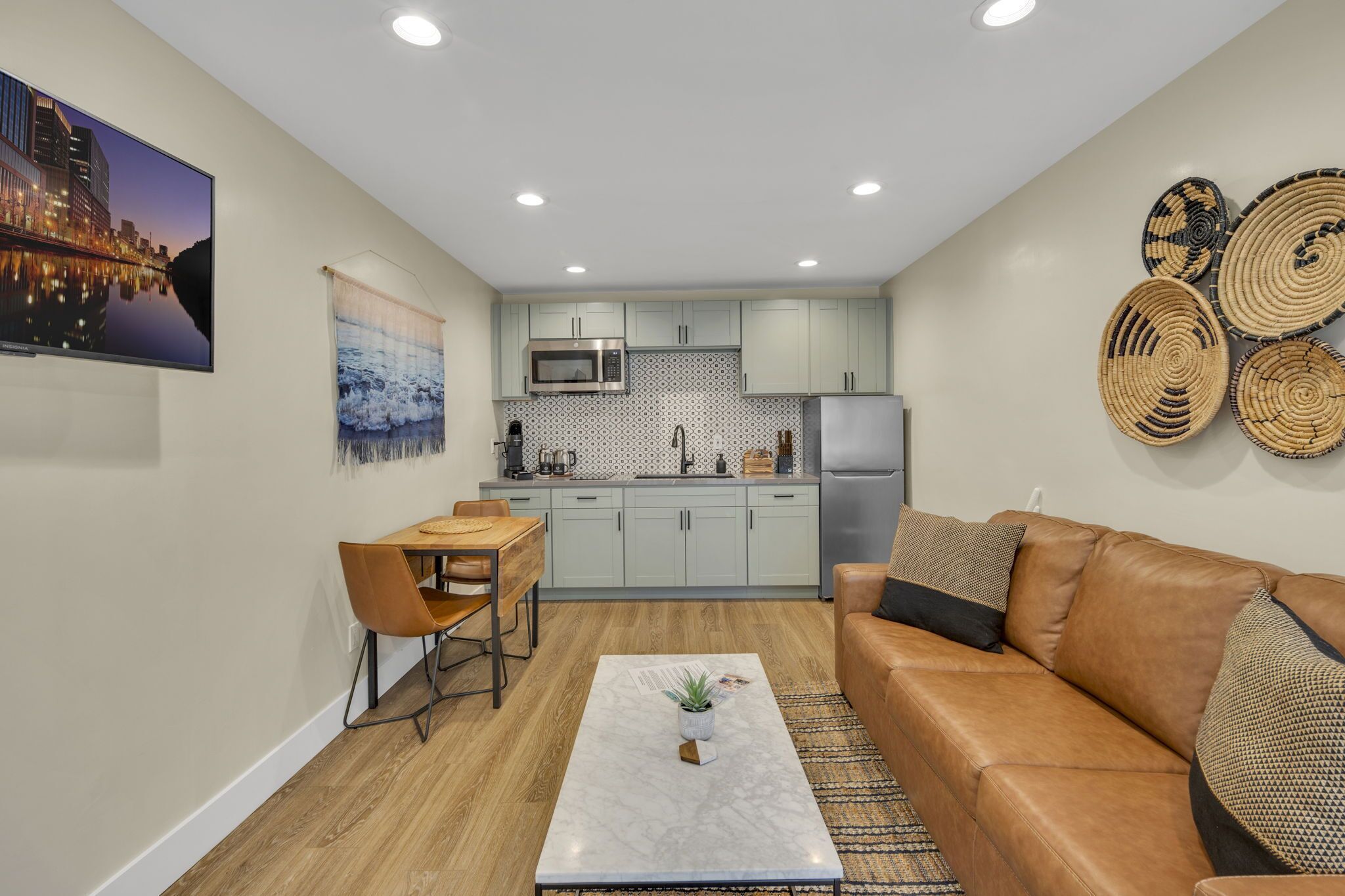 A compact living space with a kitchenette, a dining area, and a seating area with a sofa and coffee table.