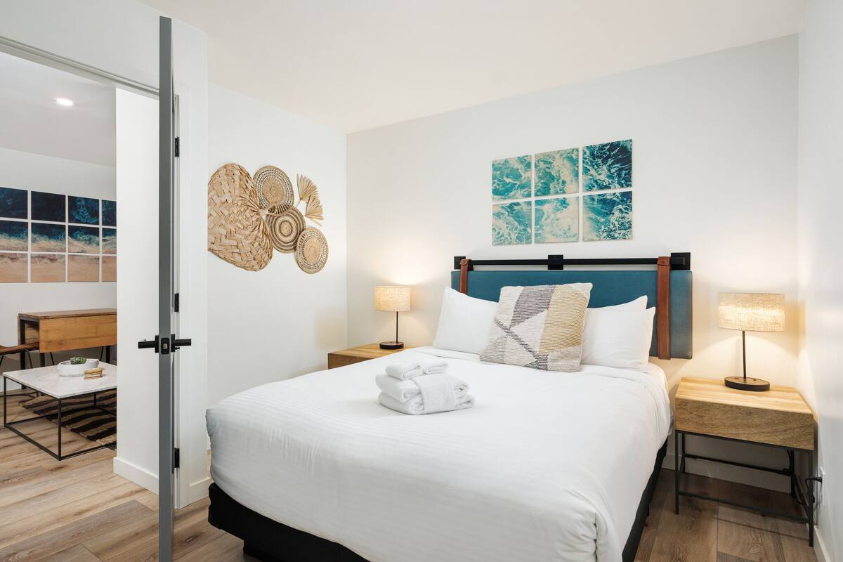 A modern hotel room with a large bed, two bedside tables, a desk, and a chair.