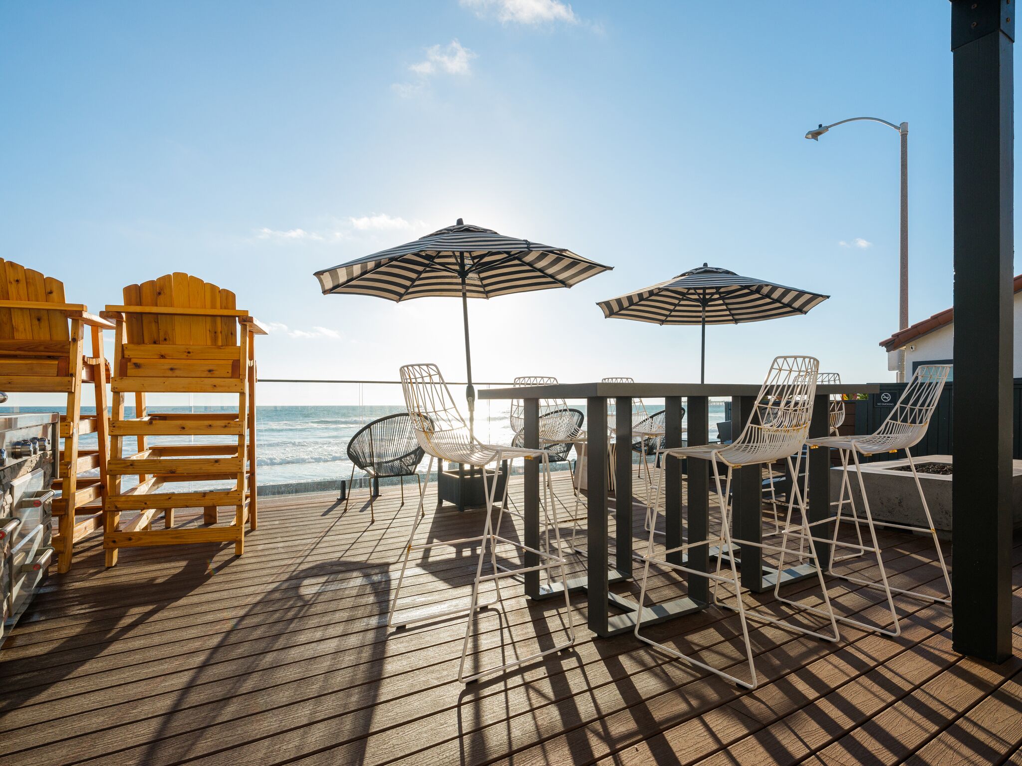 Ein Holzdeck mit Stühlen und Sonnenschirmen mit Blick auf den Ozean.