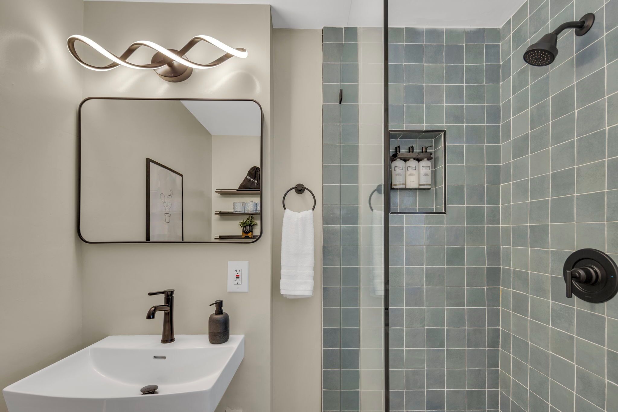 A modern bathroom with a rectangular sink, a mirror, a towel rack, and a shower area with a glass door.