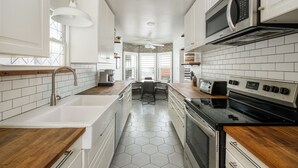 Une cuisine moderne avec des meubles blancs, une cuisinière noire, un four à micro-ondes et un sol carrelé avec des motifs hexagonaux.