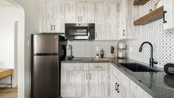 Uma cozinha moderna com uma geladeira de aço inoxidável, micro-ondas embutido e pia preta.