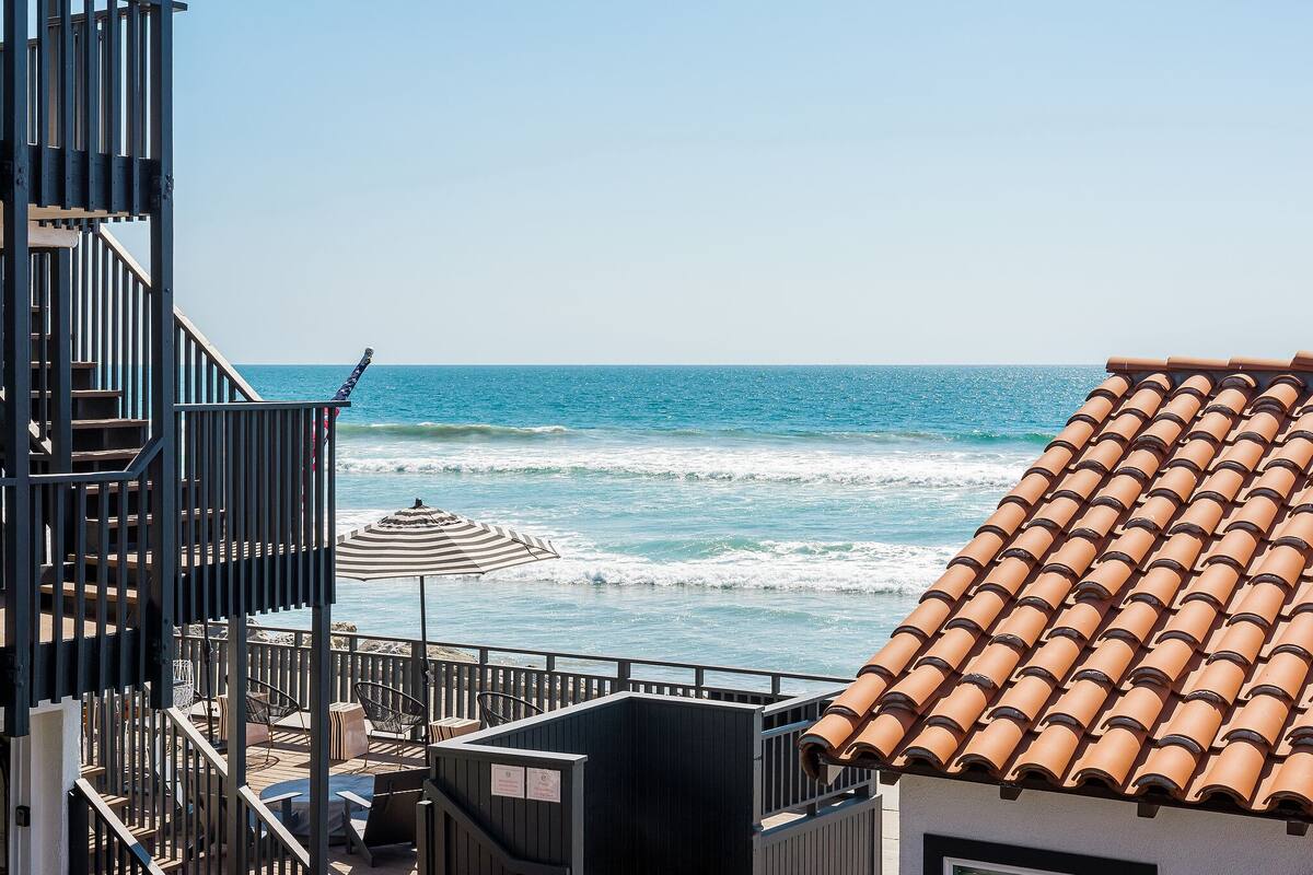 A coastal view with a terrace, outdoor seating, and a tiled roof.