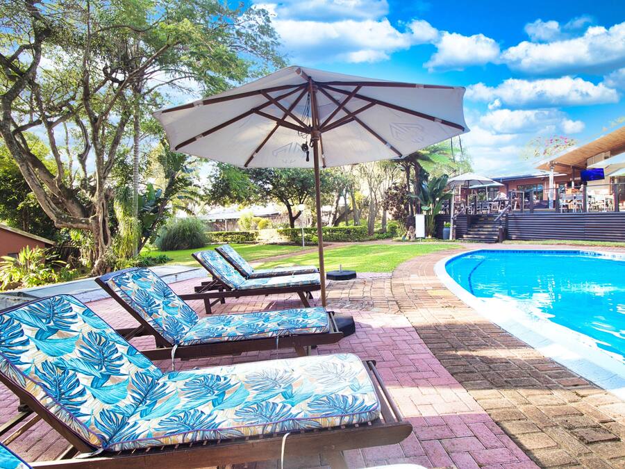 A poolside area with lounge chairs and a large umbrella.