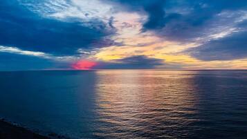 Un coucher de soleil sur une mer calme, avec un horizon dégagé.