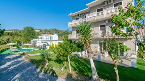 A multi-story hotel with a swimming pool, outdoor seating, and a well-maintained garden. - Akis Villa Studios & Apartments with Pool (Corfu)