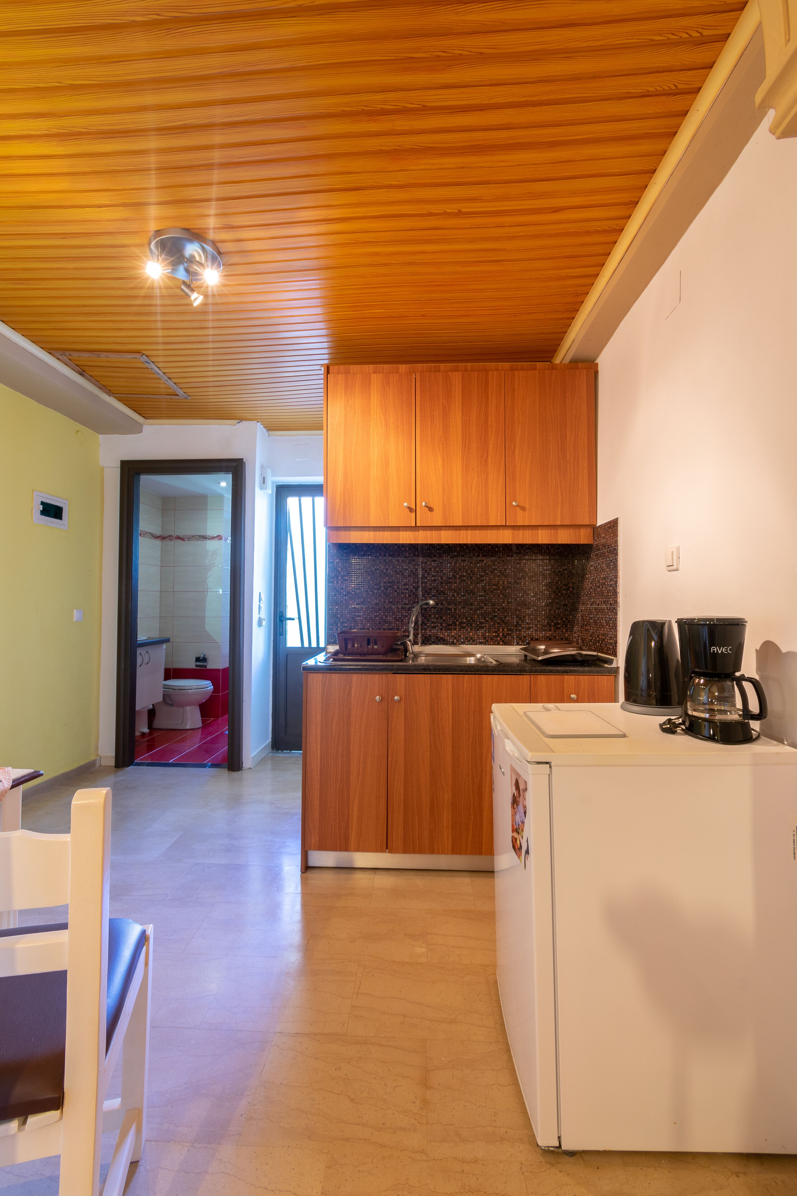 A compact kitchen with wooden cabinets, a white refrigerator, and a coffee maker.