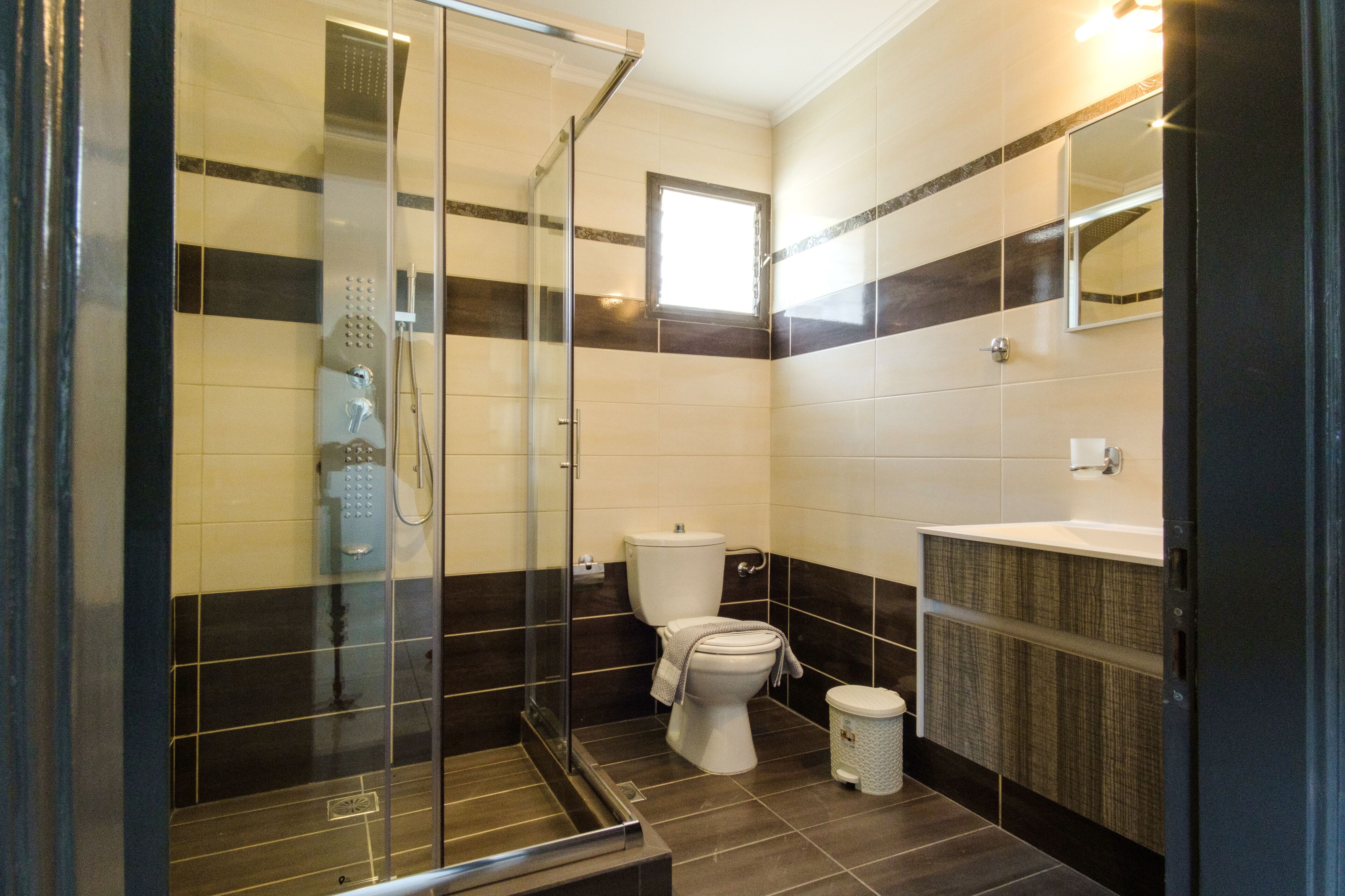 A modern bathroom with a glass shower enclosure, a toilet, and a sink.