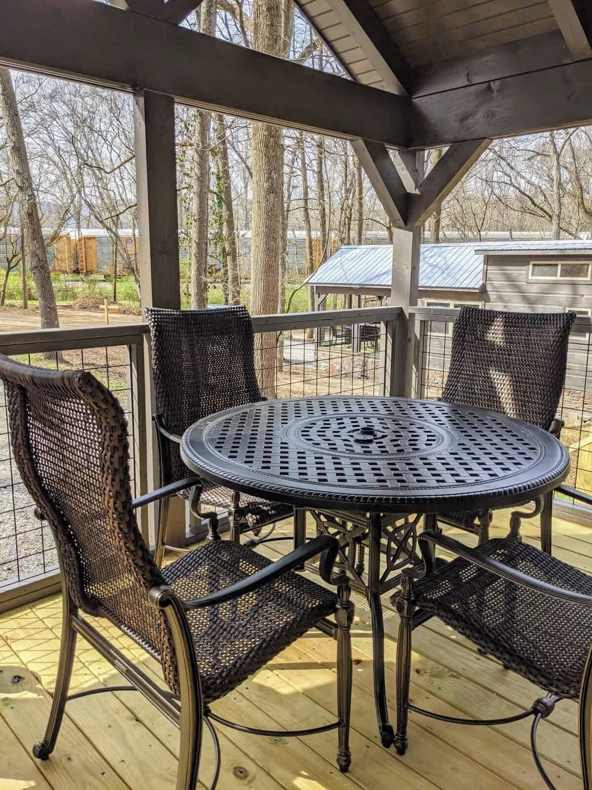 A covered outdoor patio with a round metal table and four wicker chairs.