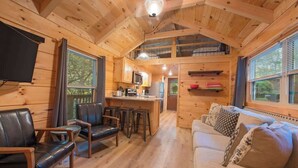 A cabin interior with a dining area, kitchen, and seating space. - Peggers Luxury Tiny Cabin at Lookout - Loaded (Chattanooga)
