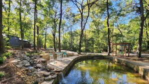 A pond with a stone border, surrounded by trees, and a gazebo with tables and chairs. - Peggers Luxury Tiny Cabin at Lookout - Loaded (Chattanooga)