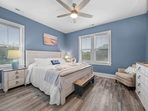 Ein Schlafzimmer mit Bett, Nachttischen, einer Bank, einem Schminktisch und einem Deckenventilator.