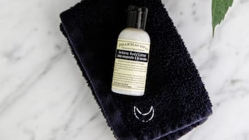 Un récipient transparent en plastique avec une étiquette, un flacon de lotion, un morceau de tissu foncé et un tournesol.