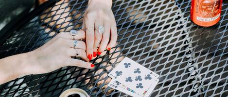 A person playing cards at a table with two cans of beer and playing cards visible.
