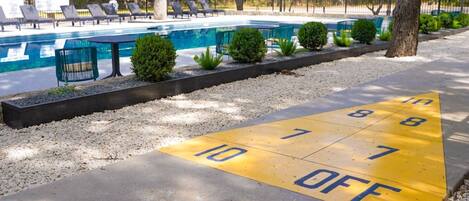 A pool area with a shuffleboard court and lounge chairs.