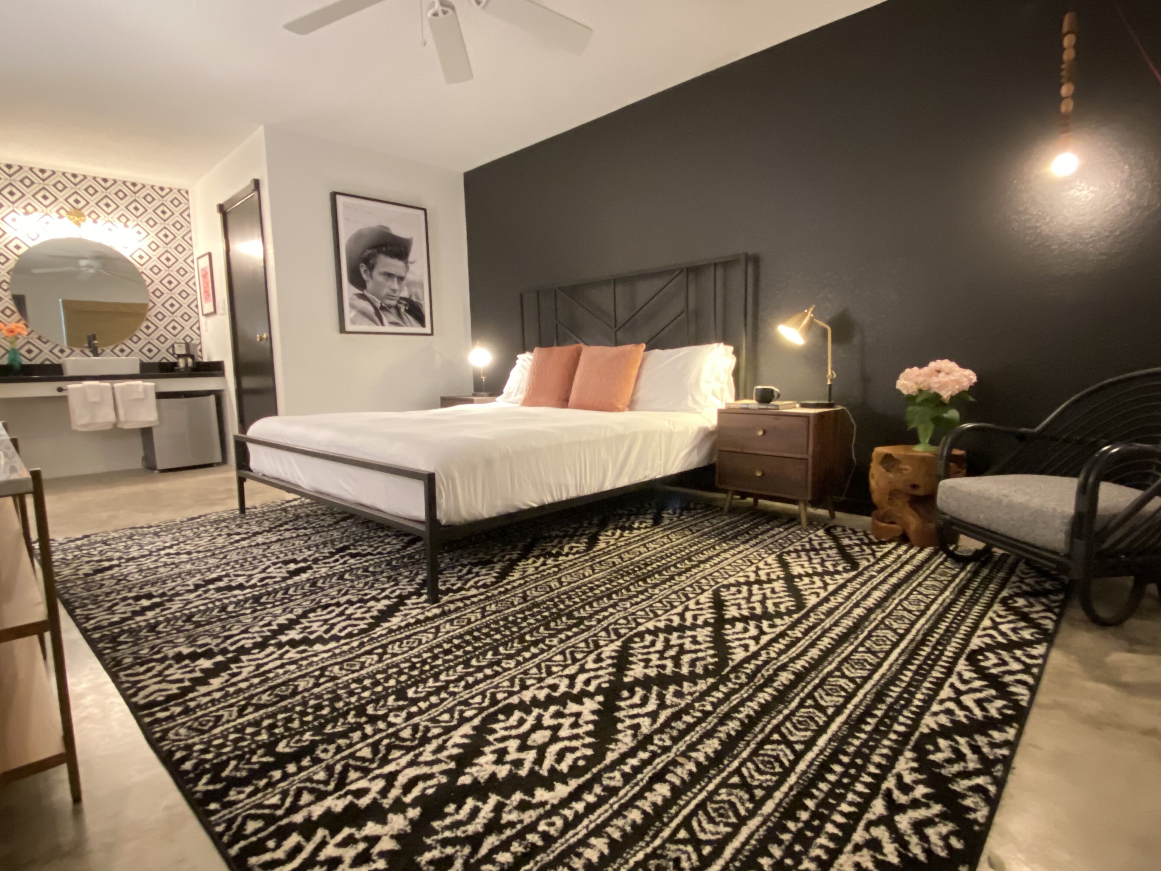 Een moderne slaapkamer met een bed, nachtkastje, stoel en een kamerkleed met dessin.