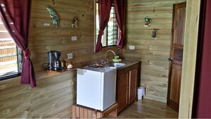 Een kleine keuken met houten wanden, een spoelbak, een witte koelkast en een koffiezetapparaat.